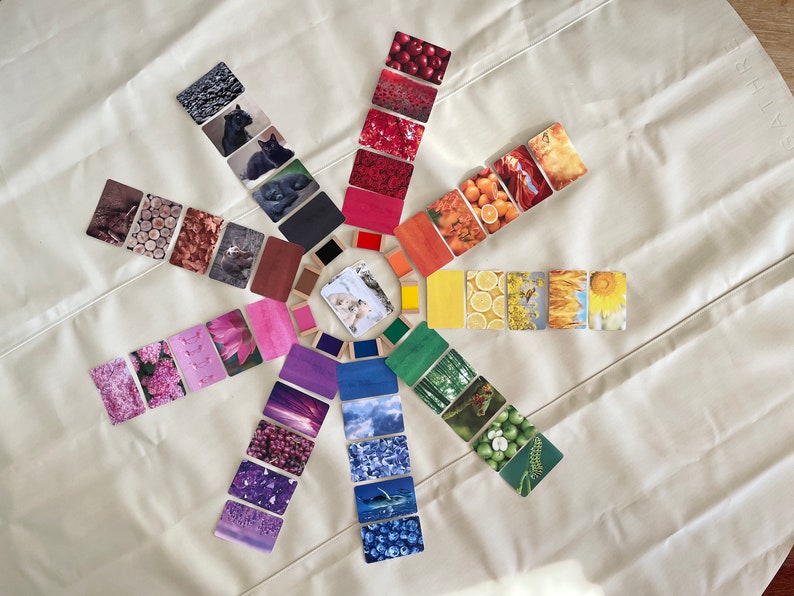 May include: A color wheel with 12 cards arranged in a circle. Each card features a different color and a corresponding image. The colors are red, orange, yellow, green, blue, purple, pink, brown, black, white, and gray.
