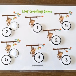 May include: A white board with the title "Leaf Counting Game" and seven monkeys hanging from branches. Each monkey has a circle with a number from 1 to 7 next to it. There are also white circles with numbers 1 to 7 that can be moved around the board.