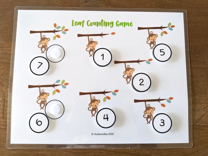 May include: A white board with the title "Leaf Counting Game" and seven monkeys hanging from branches. Each monkey has a circle with a number from 1 to 7 next to it. There are also white circles with numbers 1 to 7 that can be moved around the board.