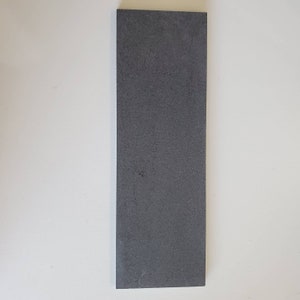 Puede incluir: Un acero de afilar rectangular de color gris oscuro para afilar cuchillos.