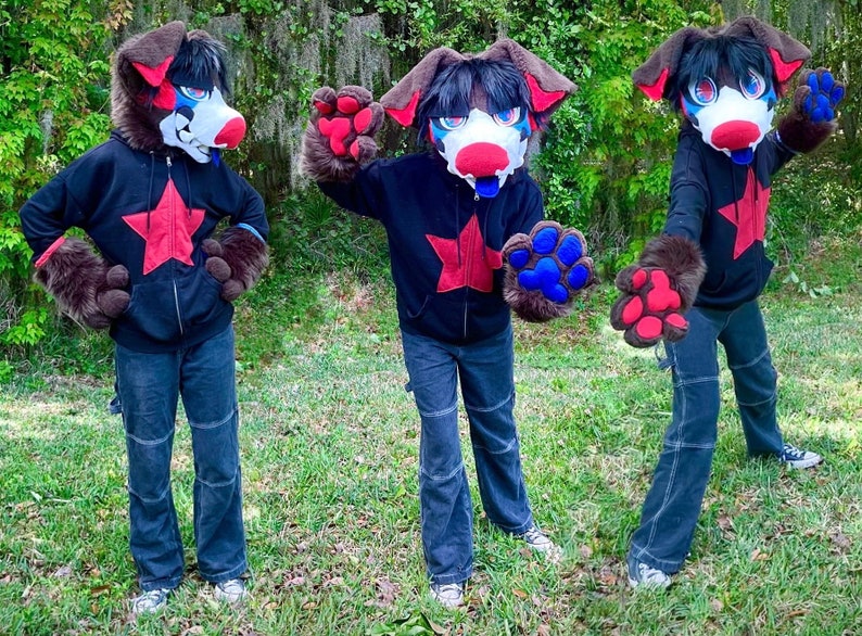 May include: Three furry dog costumes with black hoodies featuring a red star. The costumes have brown fur, red and blue paw-shaped hands, and black and white masks.
