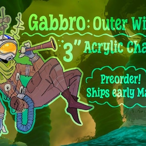 May include: A 3-inch acrylic charm featuring a cartoon astronaut character from Outer Wilds, named Gabbro. The astronaut is wearing a space suit and holding a telescope. The background is green with text that says "Preorder!"