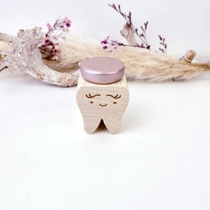 May include: A wooden tooth with a pink glitter top. The tooth has a smiling face with eyelashes.