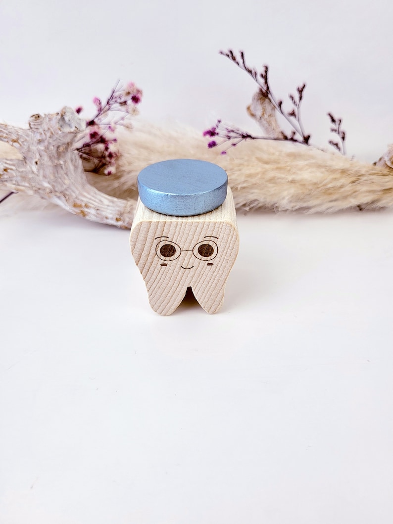 May include: A wooden tooth with a smiling face, wearing glasses and a blue top hat. The tooth is a decorative object.