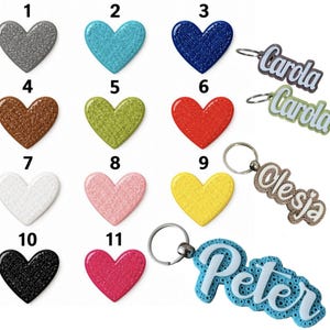 May include: A collection of eleven heart-shaped charms in various colors including gray, turquoise, blue, brown, green, red, white, pink, yellow, black, and magenta, alongside four personalized keychains featuring the names Carola, Olesja, and Peter.