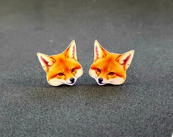 Könnte beinhalten: Ein Paar Ohrstecker mit Fuchs-Kopf-Motiv. Die Ohrstecker sind aus weißem Material mit einem roten und orangefarbenen Fuchs-Kopf-Design.