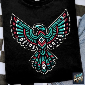 Op de afbeelding: Zwart T-shirt met een kleurrijk geometrisch adelaarontwerp. De adelaar bevindt zich in een spreidstand met een turquoise, rood en wit patroon.