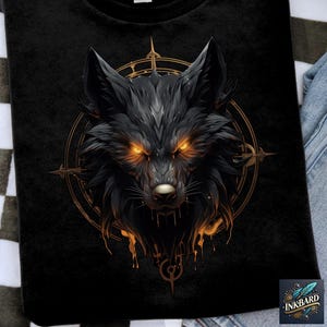 May include: Black t-shirt featuring a detailed illustration of a wolf's head with glowing orange eyes. The wolf is surrounded by a golden compass-like design. The shirt has the "INKBARD" logo in the bottom right corner.