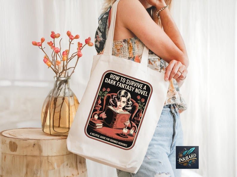 A woman is standing next to a wooden stool, holding a white tote bag with a graphic design on it. The bag features a woman reading a book and the text "How to Survive a Dark Fantasy Novel" printed on it.
