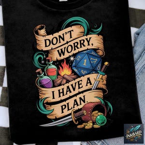 May include: Black t-shirt with a green, gold, and blue design featuring a dice, a sword, a campfire, and potions. The text on the shirt reads "Don't worry, I have a plan."