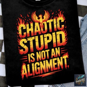 May include: Black t-shirt featuring the text "CHAOTIC STUPID IS NOT AN ALIGNMENT" in yellow and orange, with a phoenix graphic and flames. The Inkbard logo is in the bottom right corner.