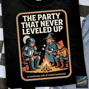 May include: Black t-shirt with a retro-style graphic featuring three fantasy characters around a campfire. The text reads "THE PARTY THAT NEVER LEVELED UP" and "A cautionary tale of wasted potential."