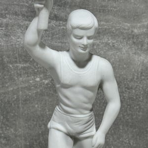 May include: White porcelain statue of a runner holding a torch. The runner is wearing a sleeveless top and shorts. The statue is highly detailed and shows the runner in mid-stride.  The piece is a collectible figurine, perfect for sports enthusiasts or those who appreciate fine craftsmanship.