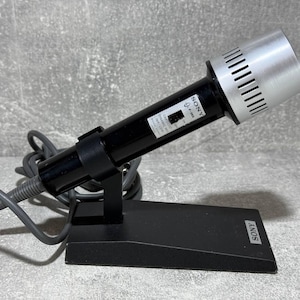 May include: A black and silver Sony microphone with a stand and a coiled cord. The microphone has a silver grill and a black body with the word "SONY" printed on it.