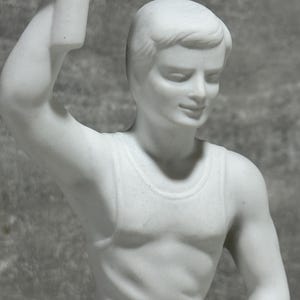 May include: White marble statue of a person wearing a sleeveless top. The statue is depicted in a dynamic pose, suggesting movement and action. The figure's musculature is subtly defined, and the overall style is classical and elegant. The smooth, polished surface of the marble reflects light, enhancing the three-dimensional form. The statue's details are finely rendered, showcasing the artist's skill in capturing human anatomy and movement. The color is consistent throughout, with no variations or shading. The statue is a testament to the enduring appeal of classical sculpture and the timeless beauty of the human form.