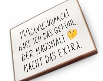 May include: White wooden sign with black text that reads "manchmal habe ich das gefühl, der Haushalt macht das extra."  A yellow emoji with a thinking face is included in the text.