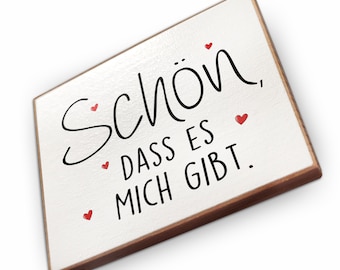 May include: White wooden sign with a brown wood frame. The sign has black text that reads "Schön, dass es mich gibt." with red hearts scattered around the text.