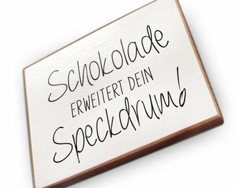 May include: White wooden sign with black text that reads "Schokolade erweitert dein Speckdrum!"