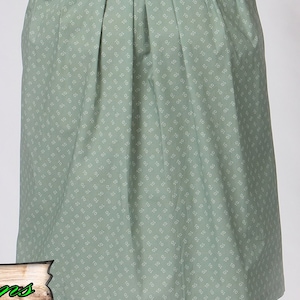 May include: A sage green skirt with a repeating white floral pattern. The skirt has pleats at the waist and a slight A-line shape. The fabric appears to be cotton or a similar lightweight material.
