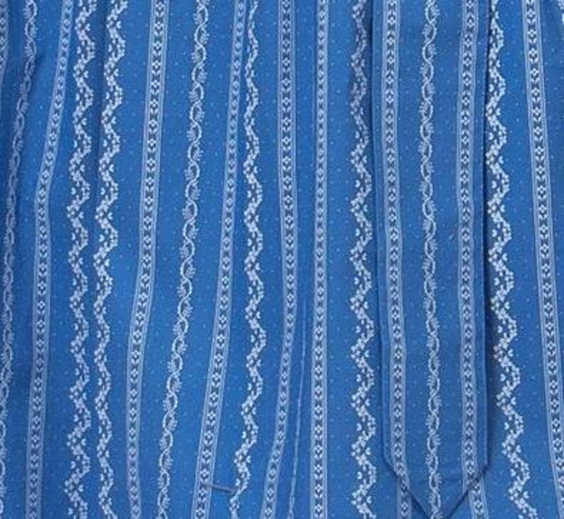 May include: Blue fabric with a white patterned design. The pattern features vertical stripes with a repeating design of small dots and a wavy line.