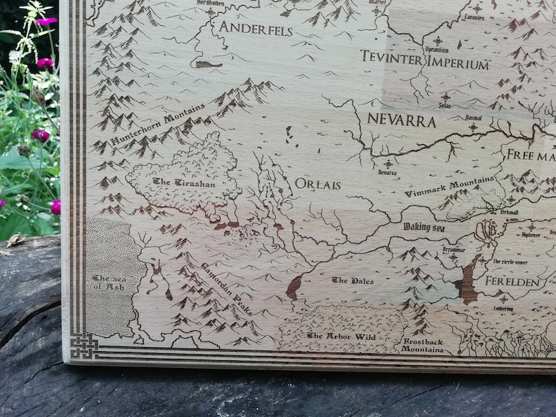 May include: A light brown wooden laser-engraved map of Thedas, featuring various regions including Ferelden, Orlais, Tevinter Imperium, and Nevarra.  The detailed map showcases mountains, rivers, and seas, with region names clearly labeled.  The wood grain is visible, adding to the rustic aesthetic.  This decorative map is perfect for fantasy fans and gamers.
