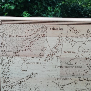 May include: A light brown wooden engraved map of Tevinter Imperium, featuring various geographical locations such as the Donarks, Anderfels, Nevarra, and the Colean and Rocen Seas.  The map includes mountains, rivers, and coastlines, all intricately detailed with brown engraved lines.  The names of the locations are clearly visible, adding to the map's detailed aesthetic. This laser-engraved wooden map is a unique piece for fantasy enthusiasts and tabletop gamers.