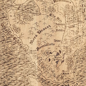 May include: A vintage-style map, reminiscent of a fantasy world, is rendered in sepia tones on a wood-like surface.  The map features various geographical elements, including a Merz Desert, Zomidlats, and the Maximal Place, along with rivers, mountains, and forests.  Names of locations like Yumene, Alebido, Tirino, and Kiash Wraps are inscribed, adding to the map's detailed and intricate design. The overall aesthetic is reminiscent of an antique, hand-drawn map, with a rustic and aged appearance.