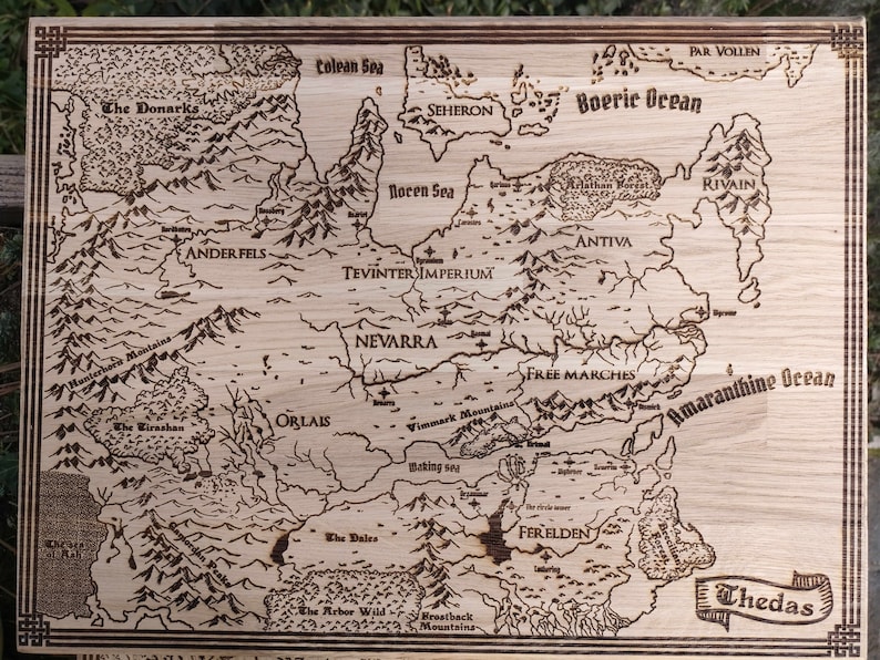 May include: A wood-burned map of Thedas, featuring various regions like Tevinter Imperium, Nevarra, Orlais, and Ferelden.  The map includes geographical details such as mountains, seas (like the Colean Sea and Amaranthine Ocean), and forests.  Names of locations are clearly labeled, making it a detailed and decorative piece. The light brown wood grain is visible through the burn marks, adding to its rustic appeal. The map is bordered with a simple frame.