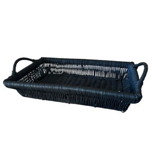 May include: A rectangular black woven basket tray featuring a flat base and vertical side walls constructed from thin, flexible material. The tray includes two curved handles, one on each of the shorter sides, integrated into the frame.