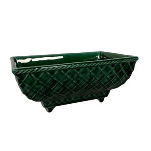 May include: A rectangular, emerald green ceramic planter with a diamond pattern and rope-like trim. The planter has three small feet and a glossy finish, suitable for indoor or outdoor use.