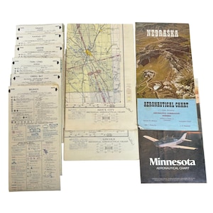 May include: A collection of vintage paper aeronautical charts including sectional maps for Sioux City and Lincoln, Nebraska, and Minnesota. The set features various regional legends, navigational data, and aerial photography of landscapes and aircraft.