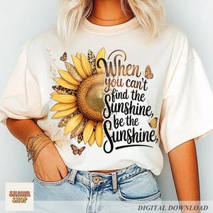 May include: Cream-colored t-shirt featuring a large sunflower design with leopard print accents and butterflies. The text "When you can't find the sunshine, be the sunshine" is printed on the shirt. The shirt is a digital download.