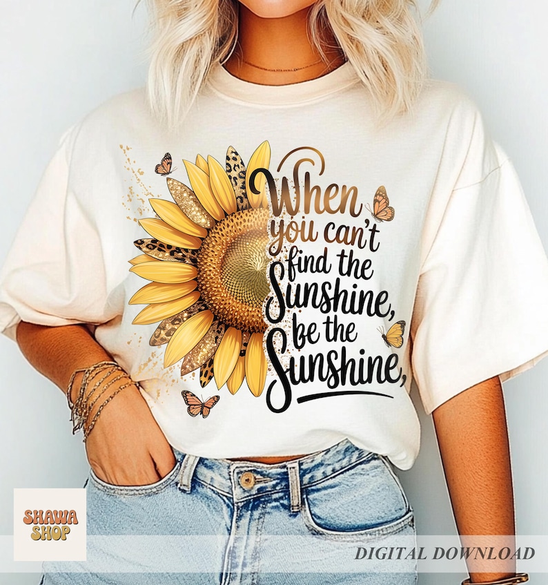 May include: Cream-colored t-shirt featuring a large sunflower design with leopard print accents and butterflies. The text "When you can't find the sunshine, be the sunshine" is printed on the shirt. The shirt is a digital download.