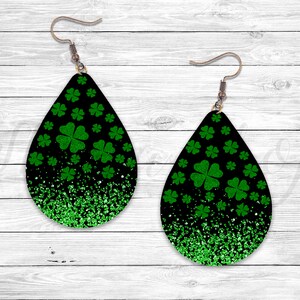 May include: A pair of black teardrop-shaped earrings with green glitter and shamrock designs.