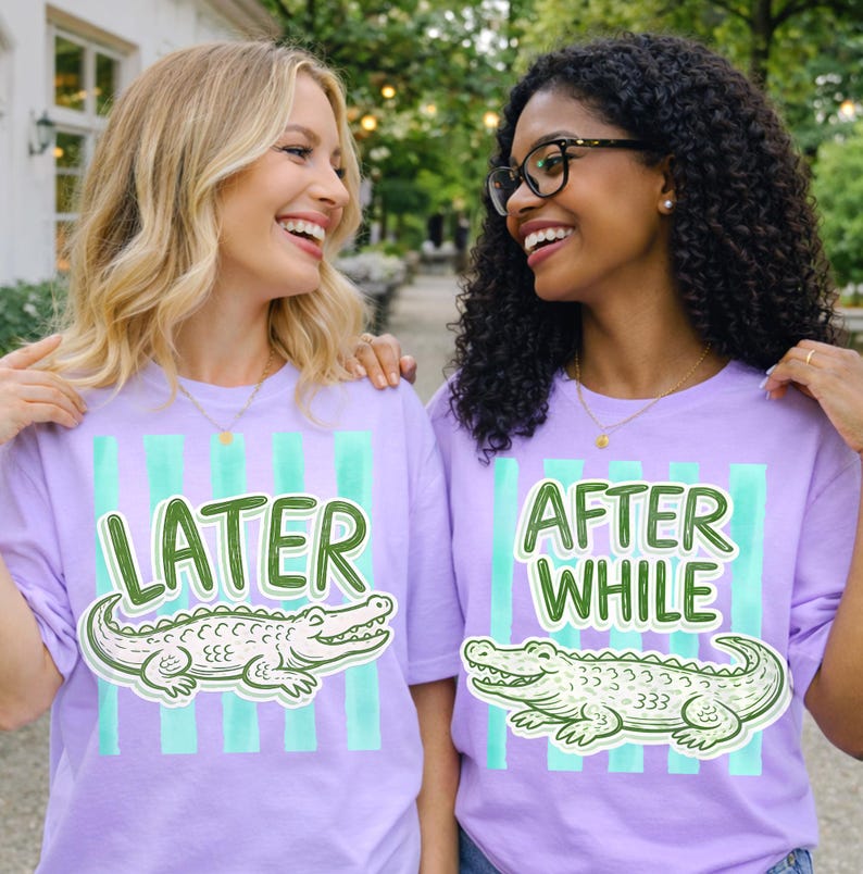 May include: Two women wearing matching lavender t-shirts with a green and white alligator graphic. One shirt says "LATER" and the other says "AFTER WHILE" in green text. The shirts have vertical teal stripes.