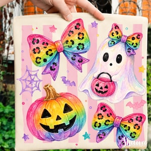 May include: A square off-white fabric pillow cover featuring a colorful print of a rainbow-colored pumpkin, a white ghost holding a pink jack-o'-lantern bucket, and three rainbow-colored bows with black leopard spots against a pink striped background.
