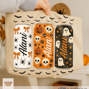 以下が含まれることがあります： ハロウィーンをテーマにした3つの飲料缶のデザインが施されたベージュのトートバッグ。缶にはクモ、リボン、カボチャ、骸骨、幽霊、星が飾られています。各缶には名前が印刷されています。バッグの上部には黒いコウモリが飾られています。