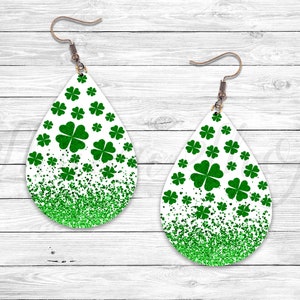 May include: A pair of white teardrop-shaped earrings with green glitter and shamrock designs.