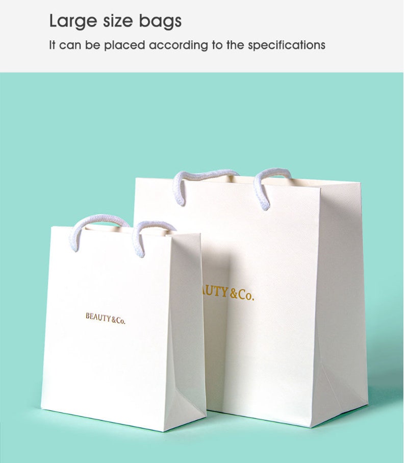 May include: Two white paper shopping bags with rope handles. The bags have the text "BEAUTY & Co." printed in gold. The bags are on a light blue background. The text "Large size bags" and "It can be placed according to the specifications" are at the top.
