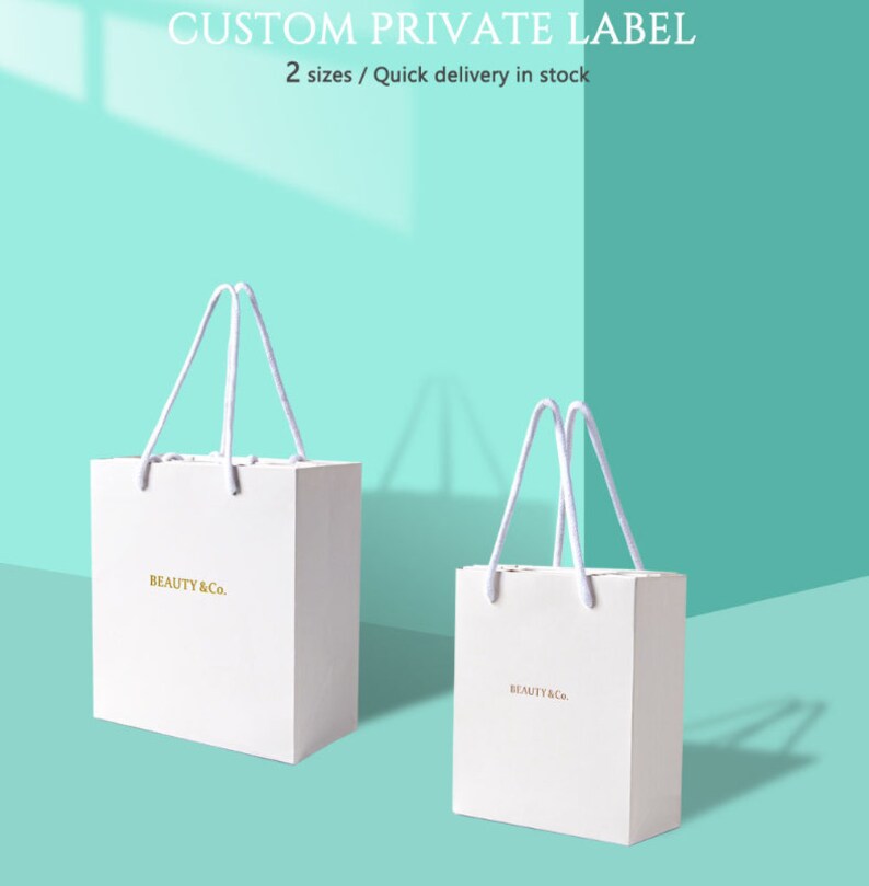 May include: Two white paper shopping bags with white rope handles. The bags have the text "BEAUTY & Co." in gold lettering. The background is a teal color with the text "CUSTOM PRIVATE LABEL" and "2 sizes / Quick delivery in stock".