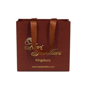 May include: A maroon gift bag with brown satin handles. The bag features gold lettering that reads "Hari Jewellers" and "Kingsbury". The website address www.harijewellers.com is printed at the bottom of the bag.