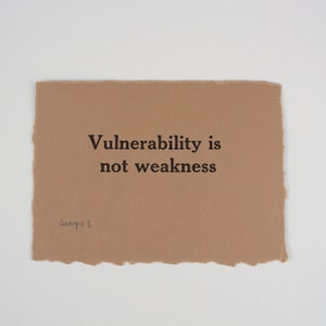以下が含まれることがあります： ベージュの紙のカードに「Vulnerability is not weakness」というテキストと「George E.」という署名があります