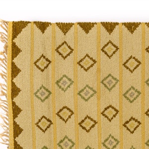 May include: A beige rug with a geometric pattern of brown and green diamonds. The rug has a fringe border.