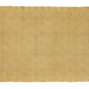 May include: A light brown rug with a diamond pattern woven into the fabric. The rug has a fringe border.