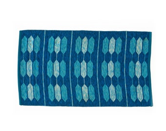 May include: A blue and white geometric patterned rug with a fringed edge.