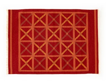 May include: Red and orange geometric patterned rug with a fringe border.