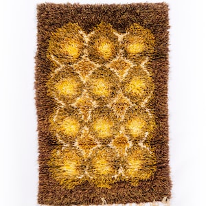 May include: A brown and yellow shag rug with a geometric pattern. The rug has a fringe border.