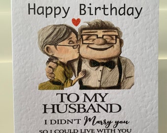 May include: A birthday card with the text "Happy Birthday" at the top. The card features an illustration of an elderly couple embracing and kissing. Below the illustration, the card reads "TO MY HUSBAND" followed by a loving message.