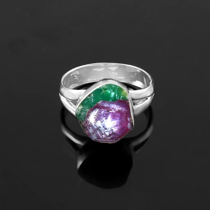 Pode incluir: Um anel de prata com uma pedra preciosa bruta. A pedra preciosa apresenta uma mistura de cores, incluindo vermelho profundo, verde e roxo. A banda do anel &eacute; de prata polida.