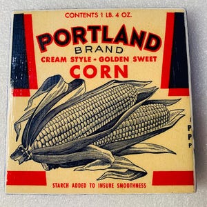May include: Vintage Portland Brand Cream Style Golden Sweet Corn can label. The label features a detailed illustration of two corn cobs with green husks. Text includes "CONTENTS 1 LB. 4 OZ." and "STARCH ADDED TO INSURE SMOOTHNESS."